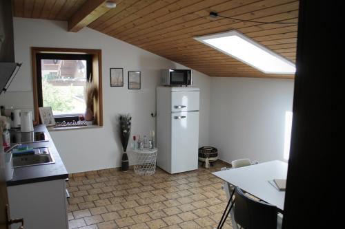 eine Küche mit einem Kühlschrank, einem Tisch und einem Fenster in der Unterkunft Ferienwohnung Bergliebe in Staudach-Egerndach