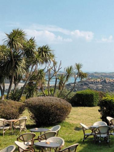 a group of tables and chairs in a field with palm trees at La Lendeline in Saint-Sauveur-Lendelin
