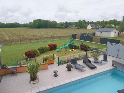 une cour avec une piscine et une aire de jeux avec un toboggan dans l'établissement Blandine & Christian, à Saint-Judoce
