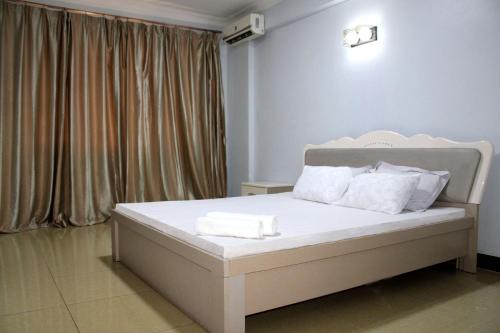 Un dormitorio con una cama blanca con almohadas blancas. en Waridi Apartment, en Dar es Salaam