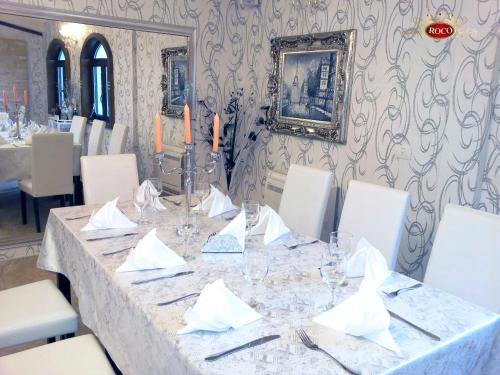 a dining room with a table with white chairs at Hotel Roco in Izvin