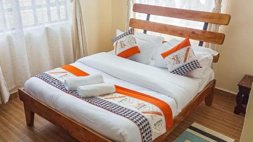 ein Bett mit orangefarbenen und weißen Kissen darauf in der Unterkunft Greenview apartments nanyuki in Nanyuki