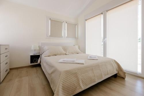 a white bedroom with a bed and large windows at Mylarakia in Chios