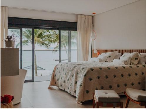 a bedroom with a large bed with a view of the ocean at Chez Louise et Louis Pé na Areia in Juquei