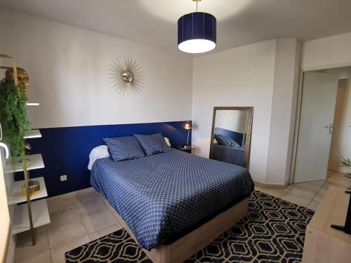 une chambre avec un lit bleu et un miroir dans l'établissement Appartement T2 à 5 min de la mer, 2 lits, à La Seyne-sur-Mer