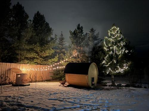 GOŚCINA u MARYNY Sauna & Balia في بورونين: ساحة مغطاة بالثلج مع حوض استحمام شجرة عيد الميلاد
