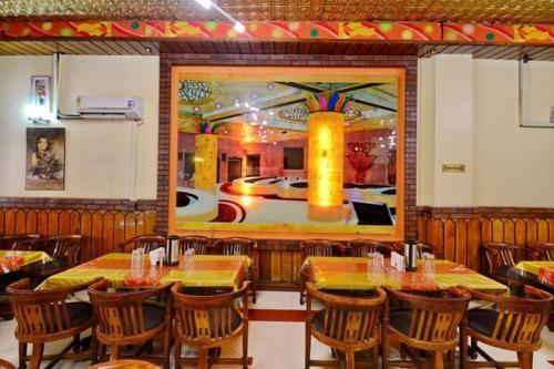 a restaurant with tables and chairs and a painting on the wall at Hotel President in Gorakhpur