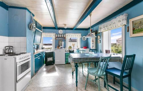 cocina con paredes azules, mesa y sillas en Cozy Home In Norddyry With Kitchen en Sætra