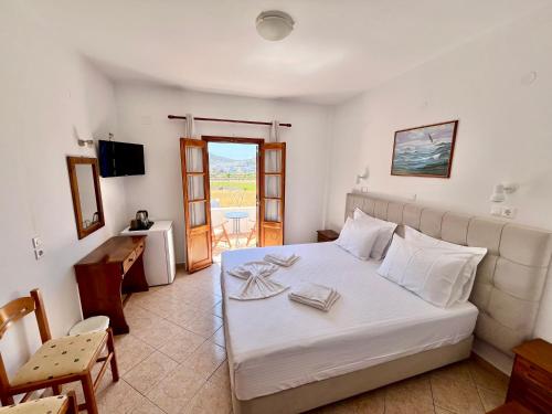 a bedroom with a large white bed and a balcony at Nicolas Studios in Skala