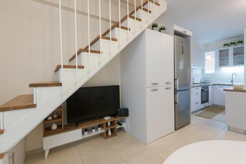 a kitchen with white walls and a staircase with a television at Mylarakia in Chios