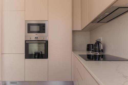 a white kitchen with a microwave and a stove at Canto 18 in Salir de Porto
