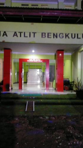 una entrada a un edificio con columnas rojas y barandilla de escalera en Hotel Grand Atlet Bengkulu en Bengkulu