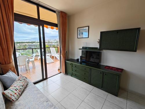 een woonkamer met een televisie en een balkon bij 1-bedroom apartment with big terrace and ocean view in Los Cristianos in Los Cristianos
