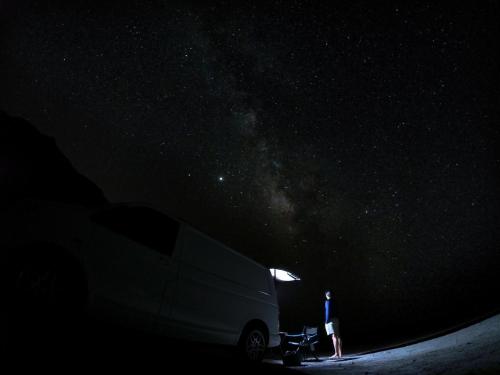 una persona parada junto a una furgoneta bajo un cielo estrellado en CAMPER GRAN CANARIA en Las Palmas de Gran Canaria