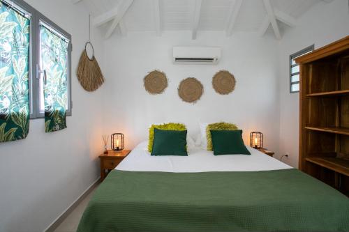 a bedroom with a white bed with green pillows at VILLA BE in Cul de Sac