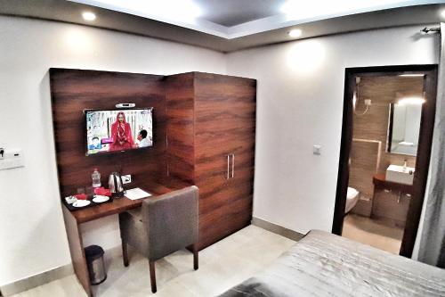 a bedroom with a desk and a tv on a wall at Hotel Delhi Aerocity in New Delhi