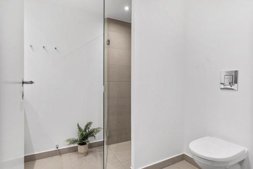 a white bathroom with a toilet and a shower at Modern luxury apartment in Aarhus