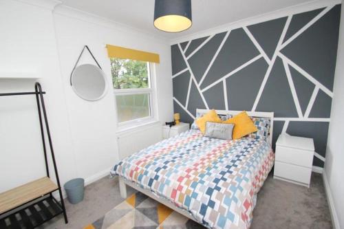 a bedroom with a bed with a geometric accent wall at The Zen Den in Southend-on-Sea