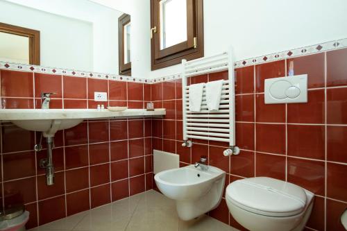 a red tiled bathroom with a toilet and a sink at Calajunco1985 - Sardinia Travel Experience in Porto San Paolo