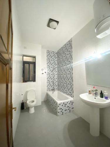 La salle de bains blanche est pourvue de toilettes et d'un lavabo. dans l'établissement Spiteri Court, à San Pawl il-Baħar