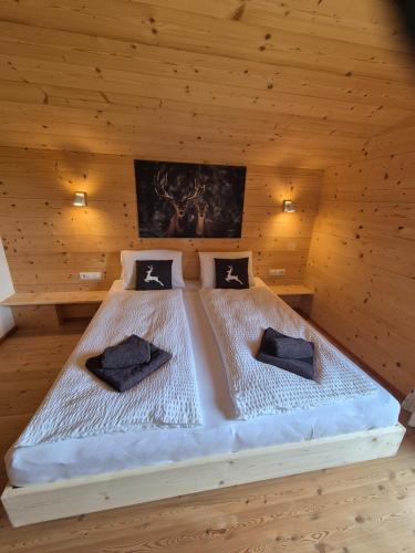 a bed in a wooden room with two pillows on it at Chalet Romana in Stumm