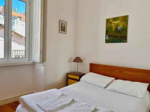 ein weißes Schlafzimmer mit einem Bett und einem Fenster in der Unterkunft 2 Bedroom, 2 Bathroom - Palma Residence in Lissabon