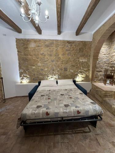 a bedroom with a bed and a stone wall at Borgo di Mezzo in Castelnuovo dellʼAbate
