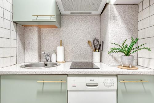 une cuisine blanche avec un évier et un comptoir dans l'établissement Peaceful Garden-Portes de Paris-METRO, à Asnières-sur-Seine