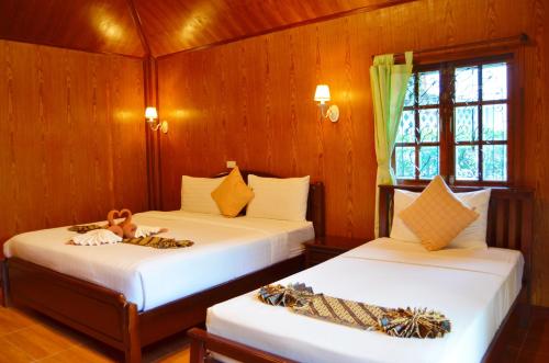 two beds in a room with wooden walls at Sayang Beach Resort Koh Lanta in Ko Lanta