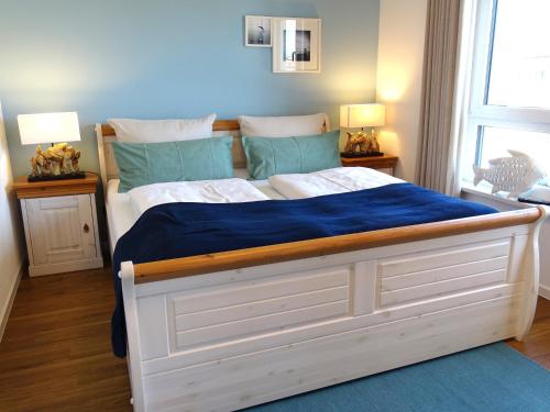 a bedroom with a large white bed with blue sheets at Gode Wind Quartiere 8 in Dahme