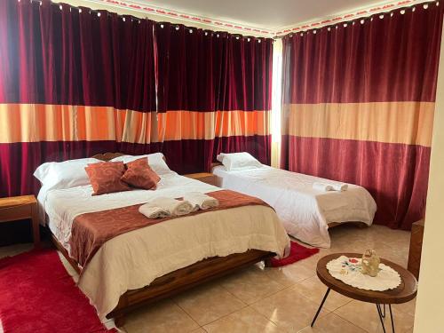 a bedroom with two beds and a table and curtains at Résidence Tianay in Antananarivo