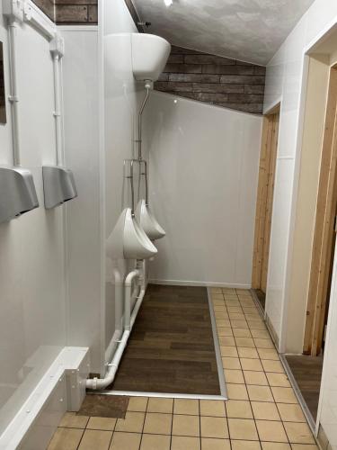 baño con paredes blancas y urinarios blancos en The New Inn, en Cinderford