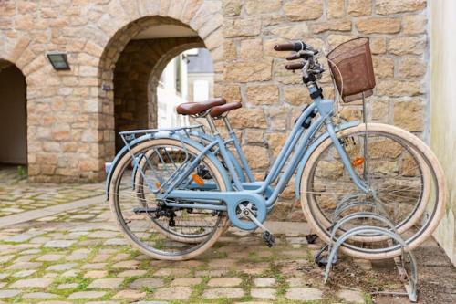 阿爾宗的住宿－La Cachette Perdue, Spa, hammam, vélos，停在石头建筑前面的一辆蓝色自行车