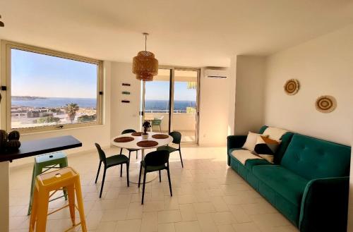 a living room with a green couch and a table with chairs at Puglia Dreaming seaview apartment in Polignano a Mare