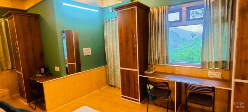 a room with a window and a table and chairs at Doris Mountain Cabins Tirthan in Banjār