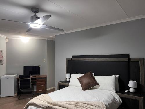 a bedroom with a bed with a ceiling fan and a desk at Bella Hideaway in East London