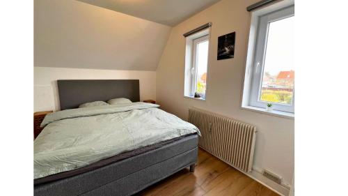 ein Schlafzimmer mit einem Bett und zwei Fenstern in der Unterkunft Cozy Holeby Pet-Friendly Villa - Puttgarden&Femern in Holeby
