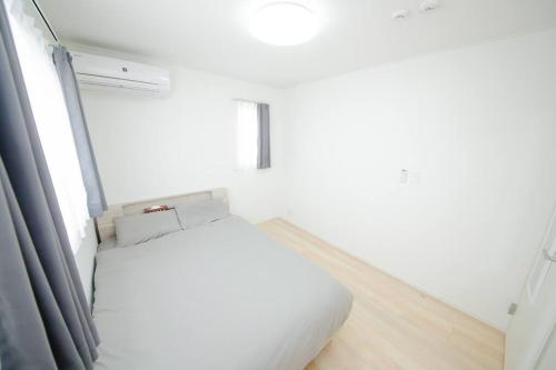 a white bedroom with a bed and a window at Piccola Locanda in Itoman