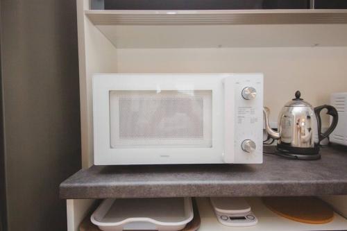 a white microwave on a shelf in a kitchen at Piccola Locanda in Itoman