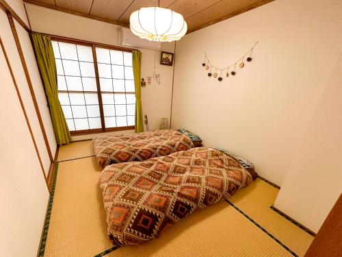 Chano Onsen House 温泉付き في Shiraoi: سريرين في غرفة مع نافذة