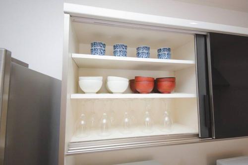 a cabinet with blue and white bowls and wine glasses at Piccola Locanda in Itoman