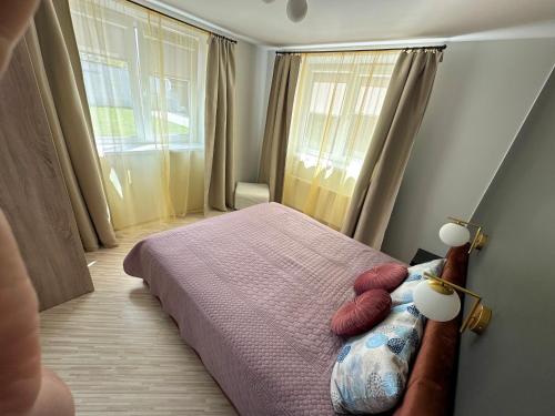 um quarto com uma cama com duas almofadas vermelhas em Maironio apartamentai em Palanga