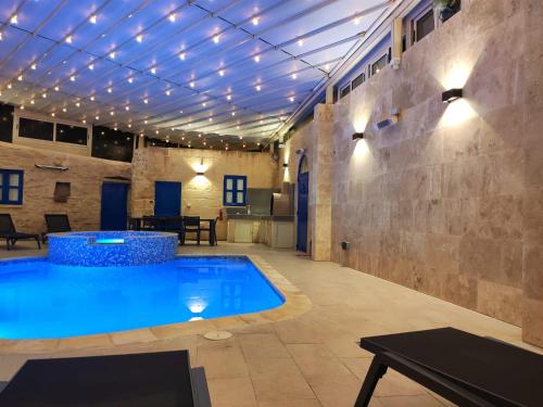 una piscina en una habitación con techo con luces en Margerita Farmhouse en Qrendi