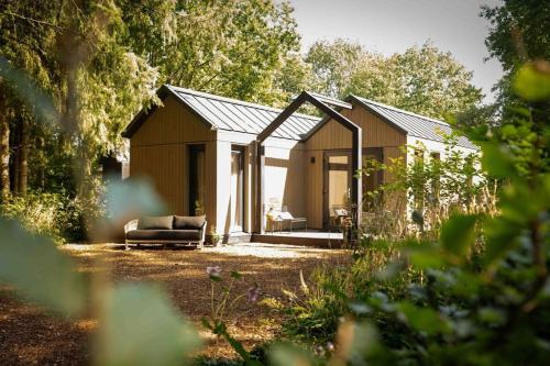 a house with a couch sitting outside of it at Sød I Tiny house in Epe