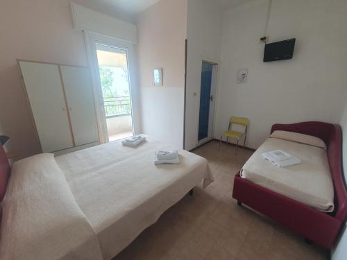 a bedroom with two beds and a window and a chair at HOTEL IDEALE young people under 40 in Rimini