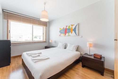 Un dormitorio blanco con una cama grande y una ventana en GuestReady - My Home in Leça, en Leça da Palmeira