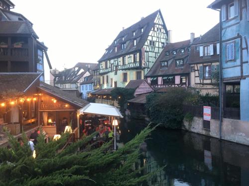 a group of people sitting at a restaurant next to a river at Le XVII - Au cœur de Colmar in Colmar