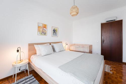 een slaapkamer met een groot wit bed en een houten kast bij GuestReady - Modernity and elegance near the sea in Vila do Conde