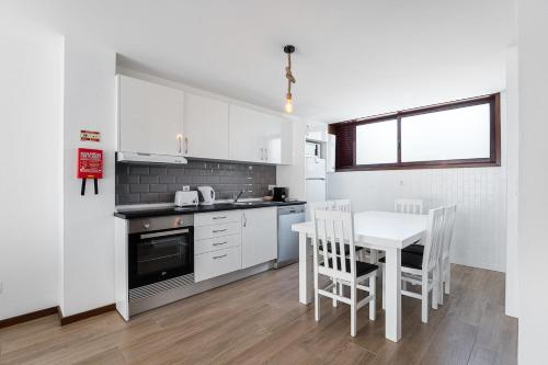 a white kitchen with a table and chairs and a table and a table at GuestReady - Esposende Beach Place in Esposende