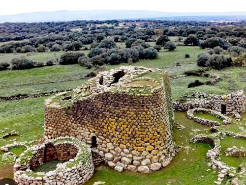 un vieux bâtiment en pierre sur un champ herbeux dans l'établissement Figu Morisca Silì, à Silì